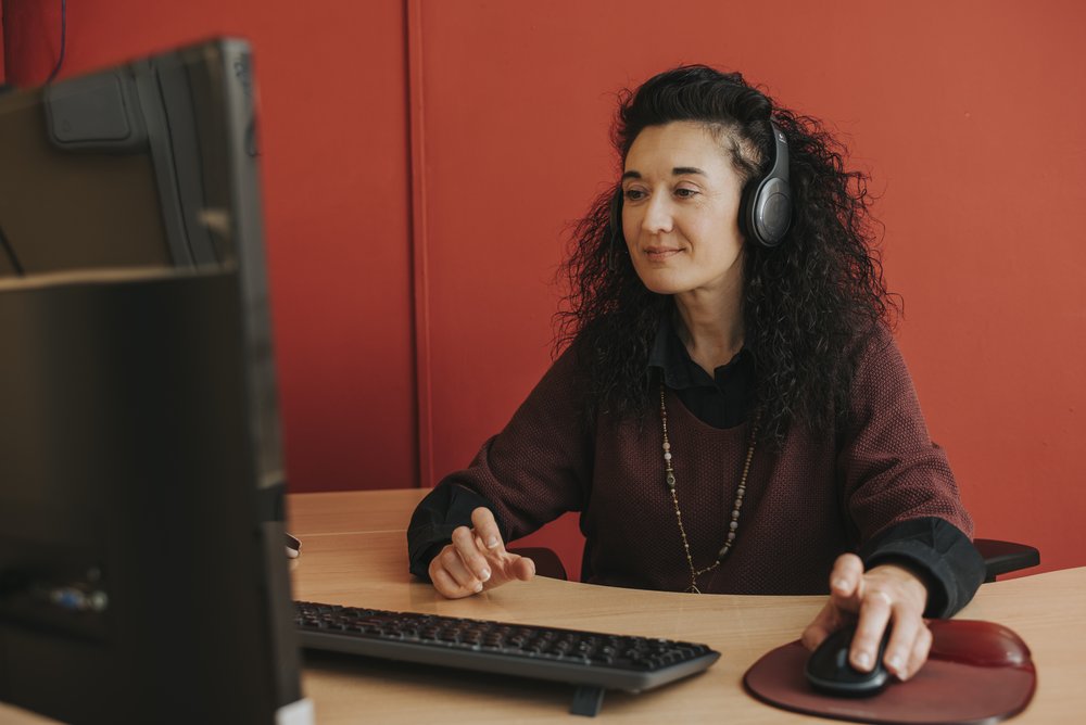 Kobieta w słuchawkach na uszach pracuje przed komputerem